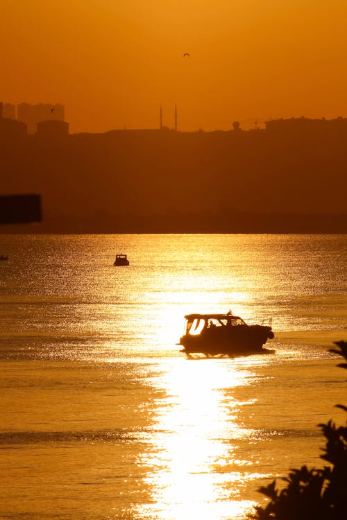 Small boat crossing golden water at sunset