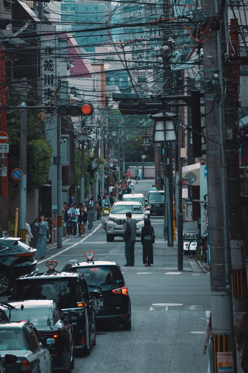 Dense city street with overhead cables and parked cars